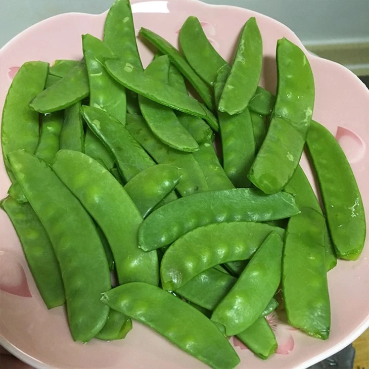 Snow pea pod shape and surface condition Whole green snow pea pods displayed after thawing or brief cooking