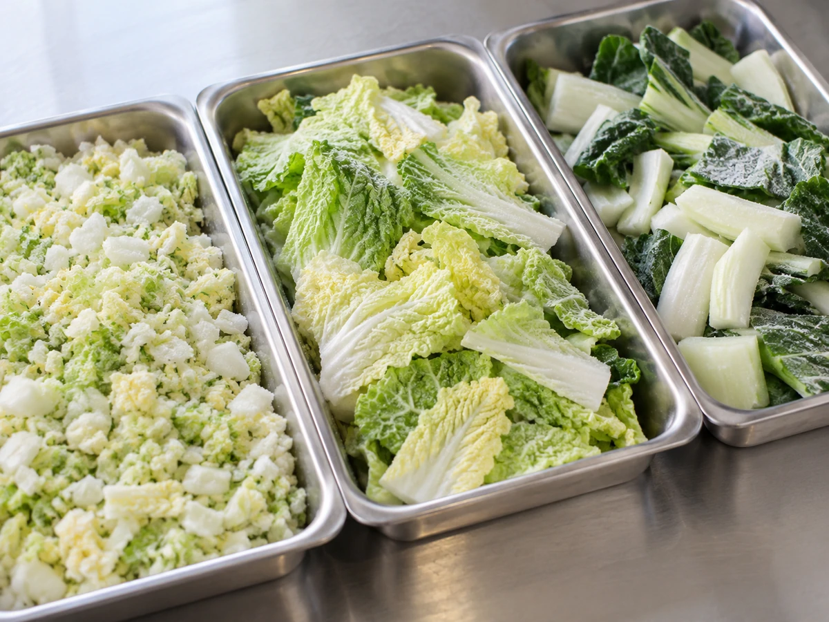 Trays of fine chopped napa, broad napa pieces and bok choy stalk and leaf cuts