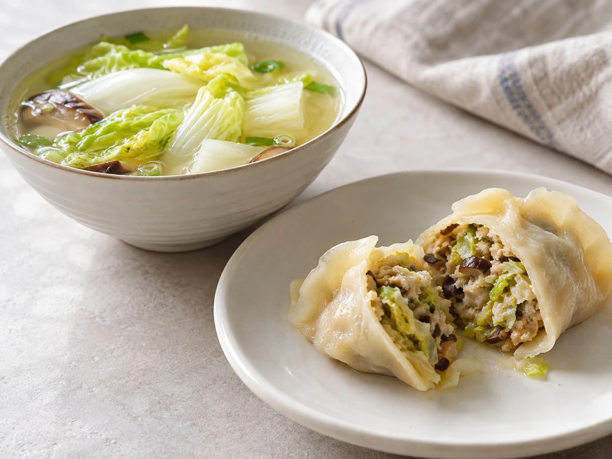 Napa cabbage soup beside a cut cooked dumpling with cabbage and mushroom filling