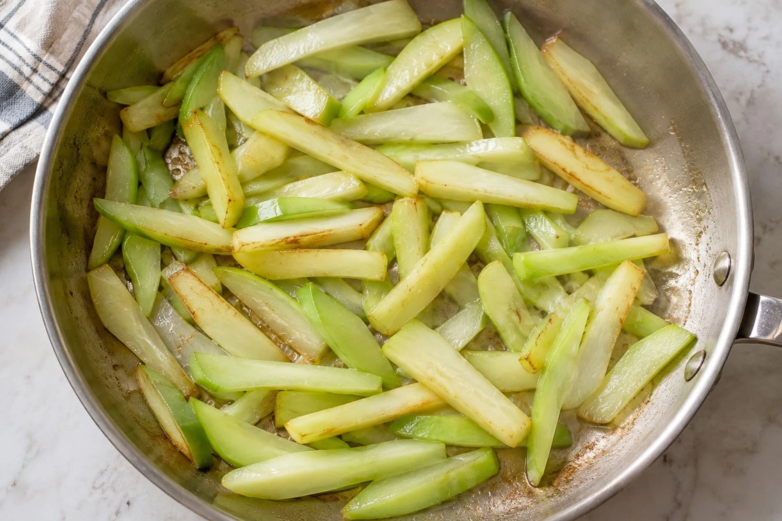 A shallow layer of chayote strips with visible spaces in the pan A shallow layer of chayote strips with visible spaces in the pan