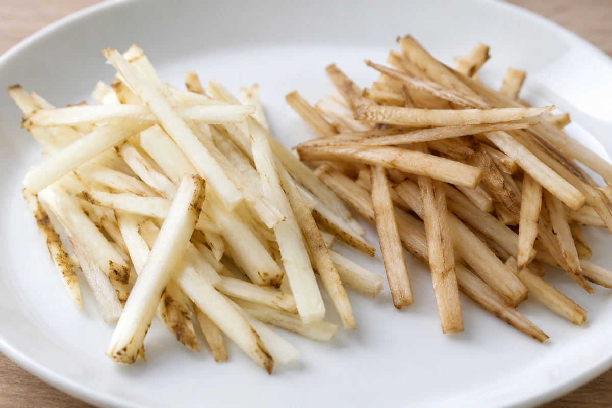 Pale and tan burdock strips placed side by side on a white plate Pale and tan burdock strips placed side by side on a white plate