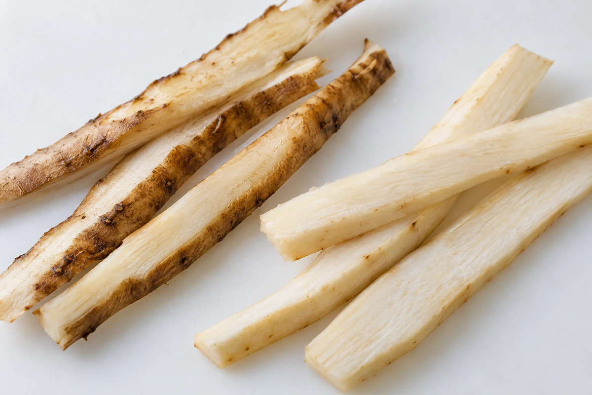 Close view of burdock strips with attached brown skin beside pale scraped strips Close view of burdock strips with attached brown skin beside pale scraped strips