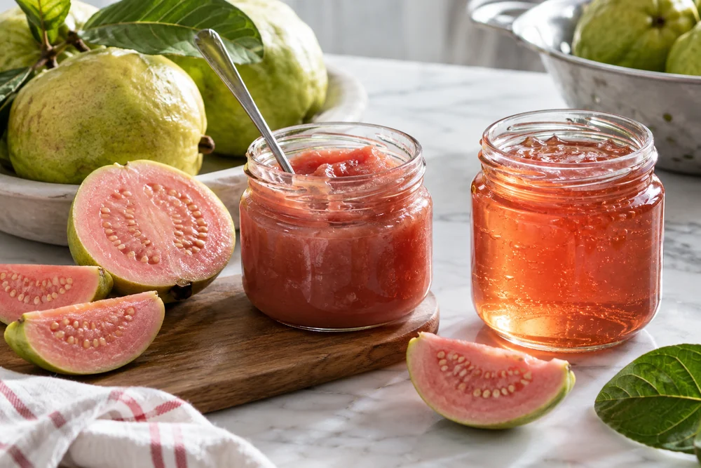 Open jars comparing opaque pink jam and translucent amber-pink jelly