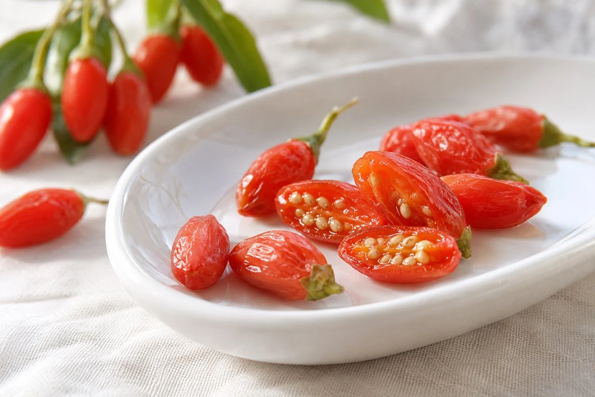 Fresh whole and cut goji berries on a white plate