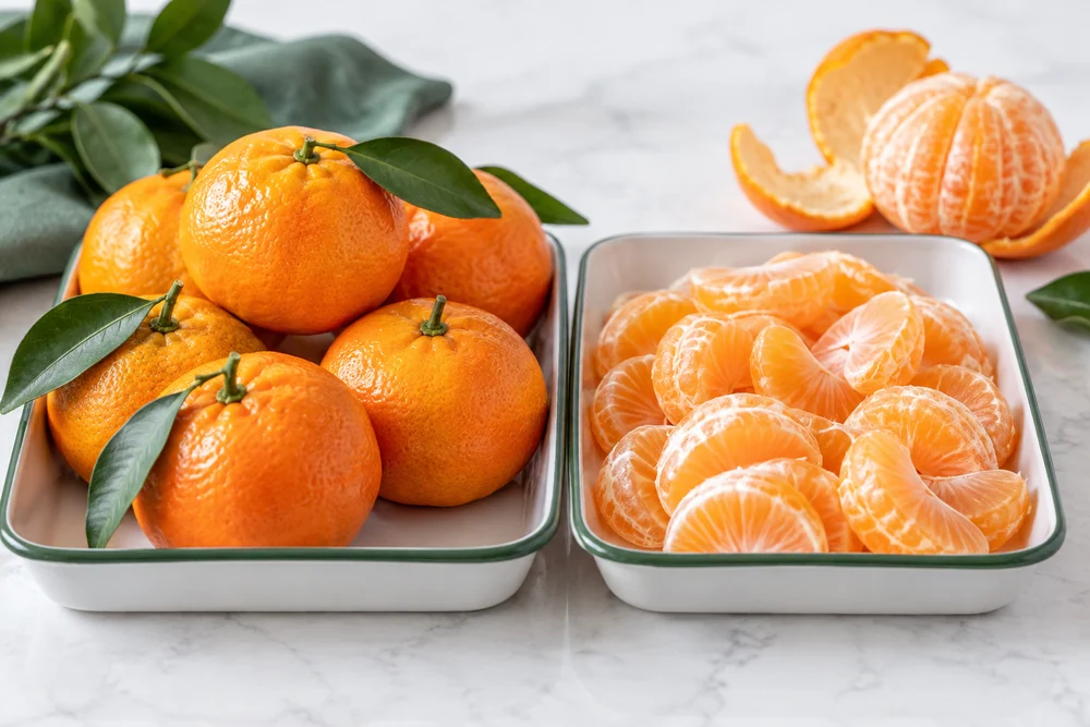 Whole-fruit and segment processing stages Whole mandarins beside peeled natural segments