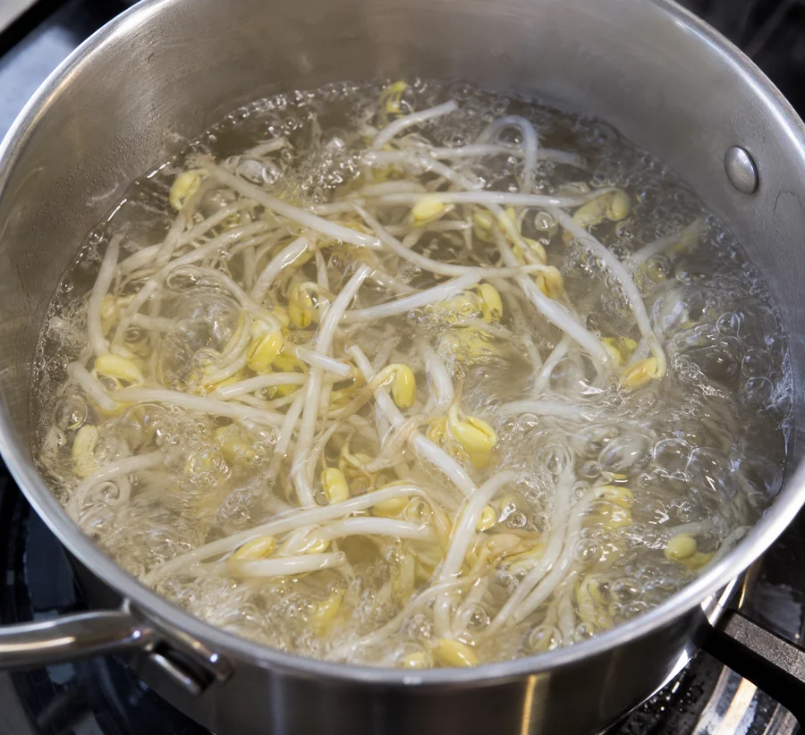 Small batch of mung bean sprouts fully immersed and moving in a pot of boiling water, no oversized crowded pot