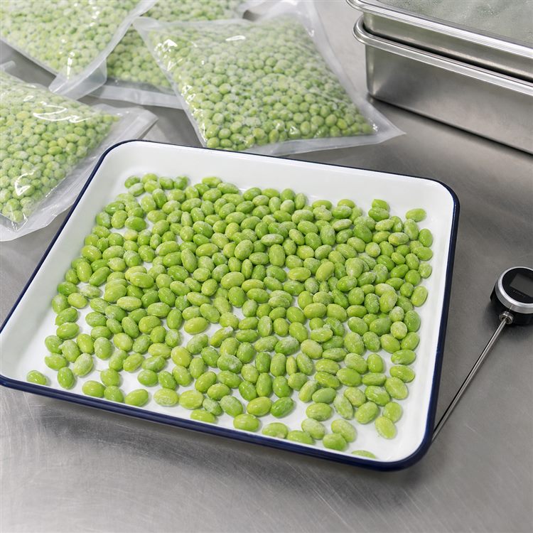 Shelled edamame product sample Shelled edamame beans spread on a tray beside packed kernels